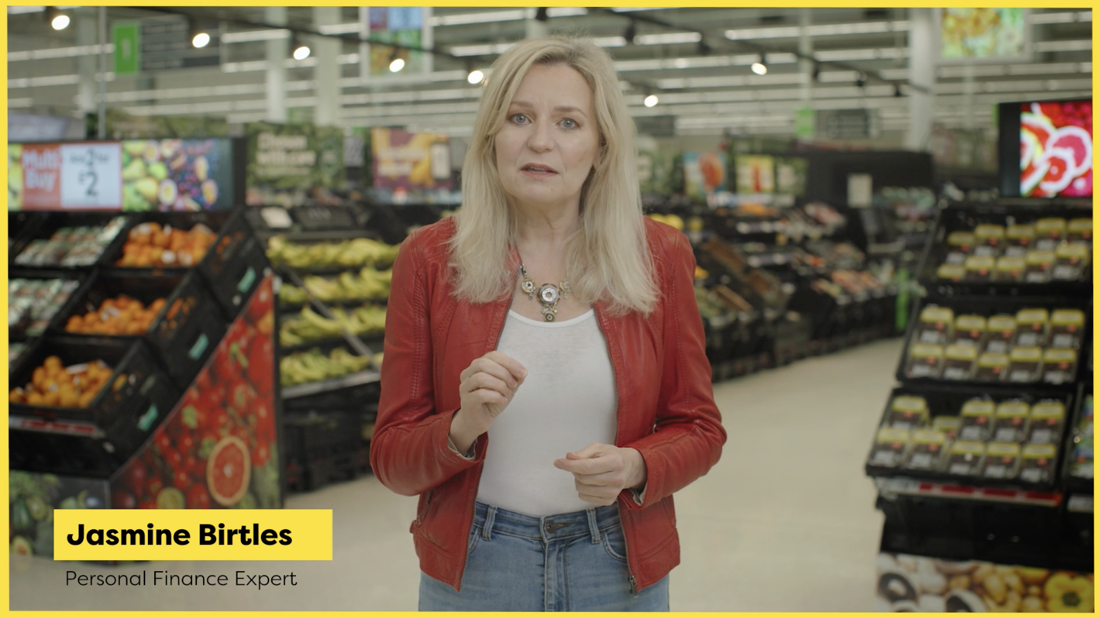 A woman in a red jacket is standing in a grocery store.