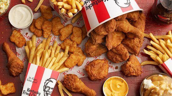A table topped with buckets of fried chicken and french fries.