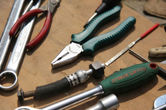 Assorted hand tools, including pliers, screwdrivers, and wrenches, laid out on a workbench.