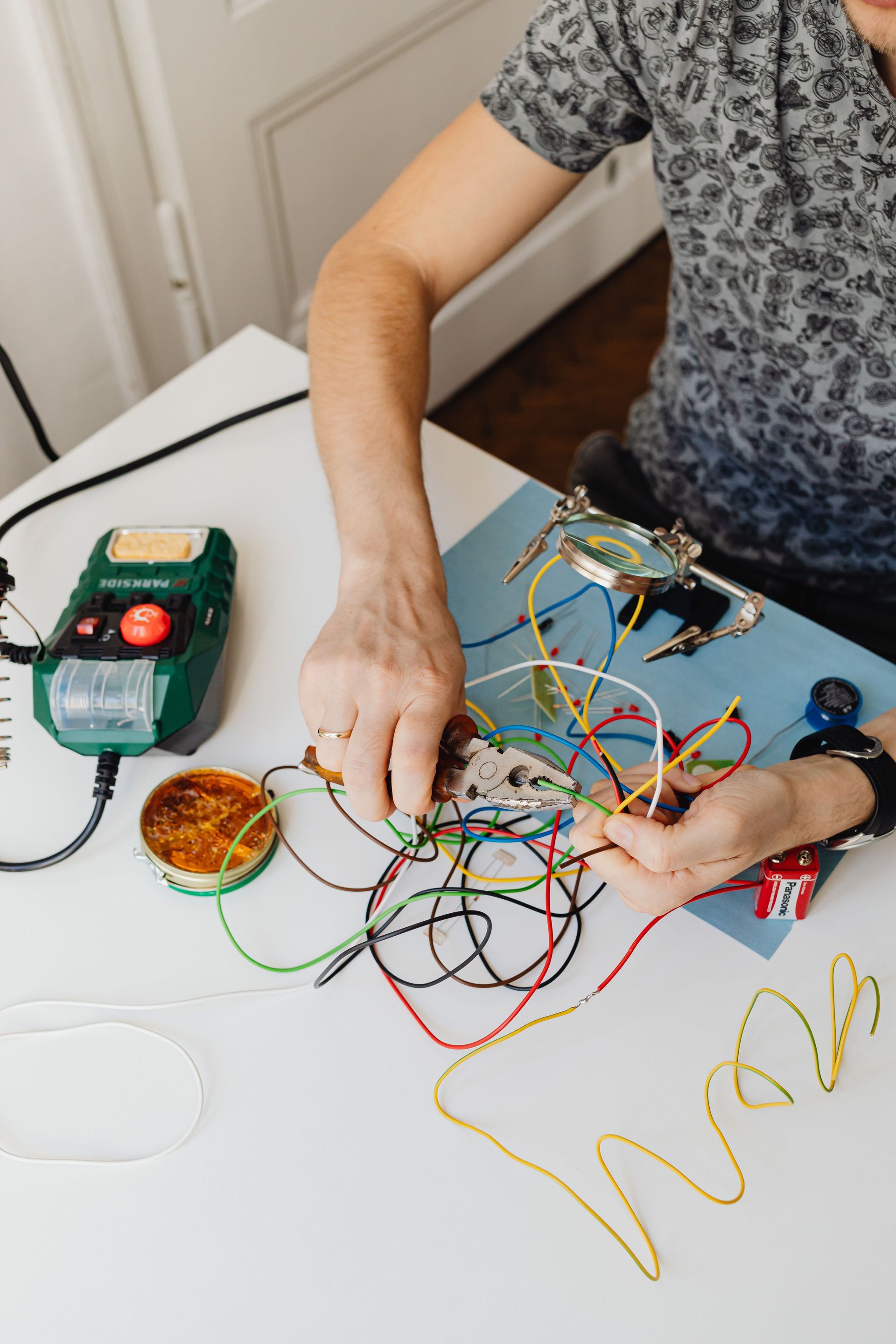 Person wiring a small electronics project with colorful wires on a white table