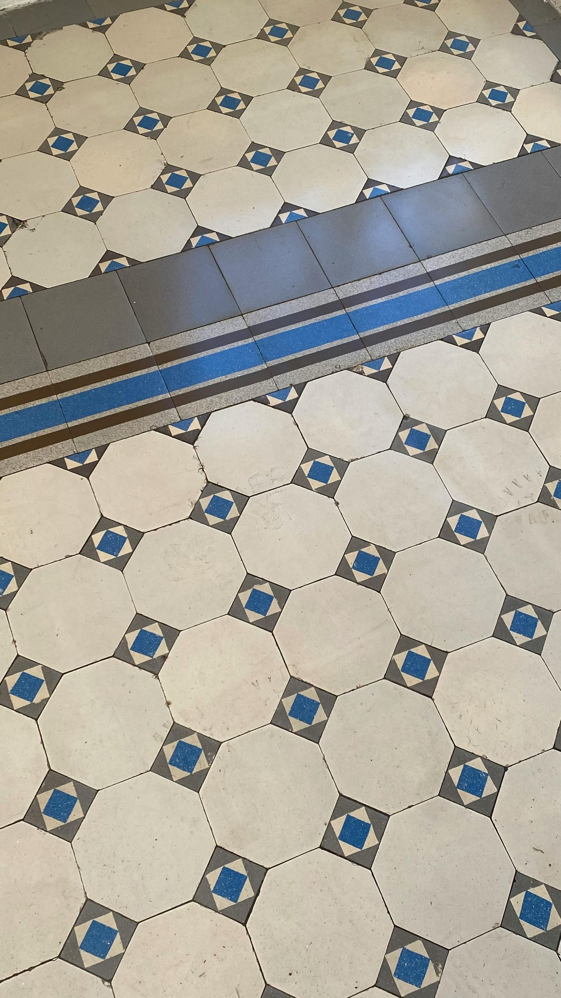 Patterned tile floor with white octagonal tiles, blue accents, and a dark threshold strip across the middle