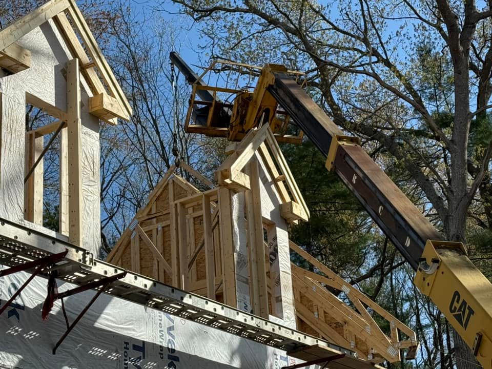 Construction site: yellow CAT forklift lifting wood framing onto a building under construction on a sunny day.