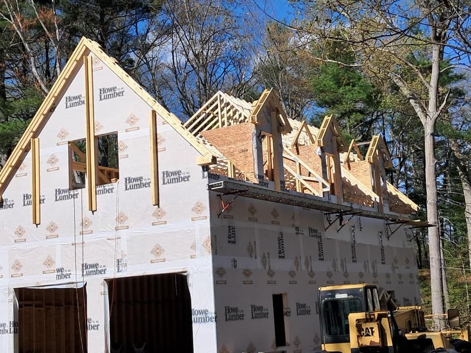 Garage under construction with roof framing. Partially covered in sheathing, with a CAT bulldozer visible.