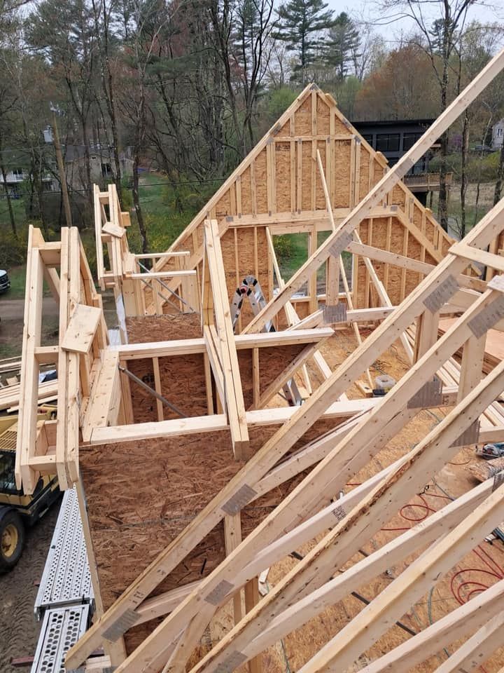 Wooden house frame under construction, with roof trusses and exterior walls.