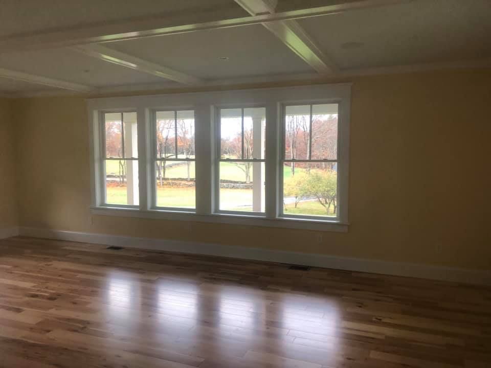 Room with hardwood floor, three windows with white trim, and a coffered ceiling.