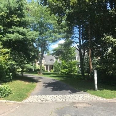 A long driveway leads to a large house surrounded by trees.