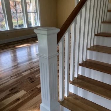 Wooden staircase with white spindles and a decorative newel post.