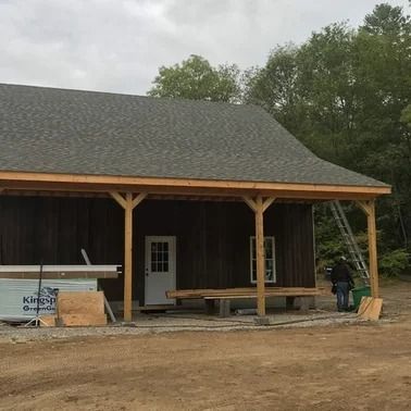 Building exterior with a covered porch. A person stands near a ladder.