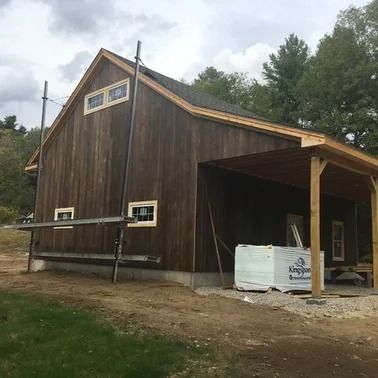 A brown wooden building under construction with a covered porch; scaffolding on the side.