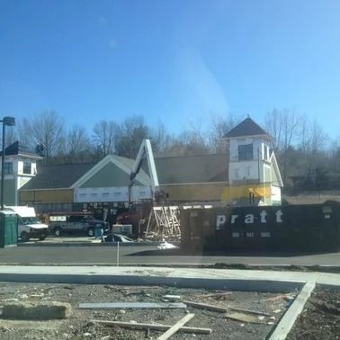 Building under construction, trees in background, sunny day. Pratt dumpster visible.
