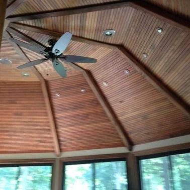 Wooden ceiling with a ceiling fan and recessed lights. Windows along the bottom.