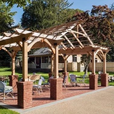 Wooden pergola with red brick pillars over an outdoor seating area.