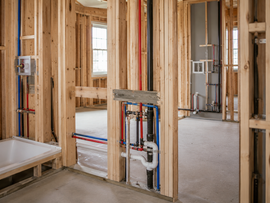 Unfinished house interior with exposed wood framing and visible plumbing and electrical lines