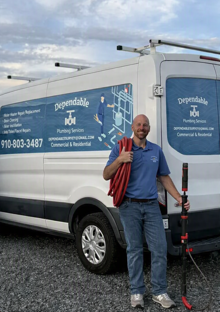 Man standing beside a white van with blue signage, holding a red bag and scooter outdoors under cloudy skies