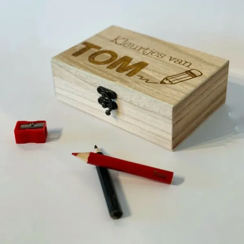 Houten doos met daarop naam gegraveerd, afgebeeld met een rood potlood op een witte achtergrond.