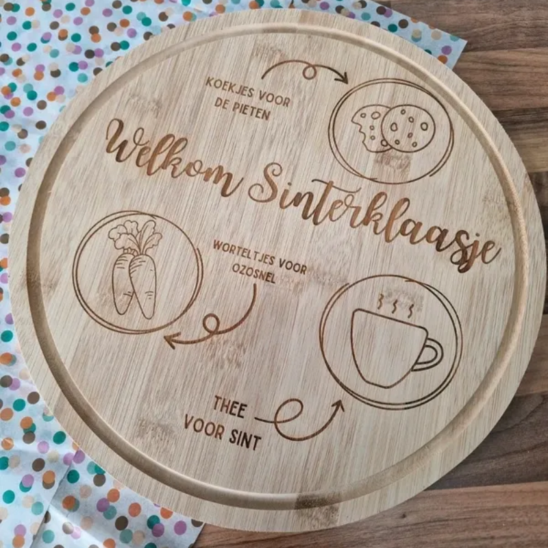 Ronde houten Sinterklaasschaal met gegraveerde iconen en Nederlandse tekst op een stippenachtergrond.
