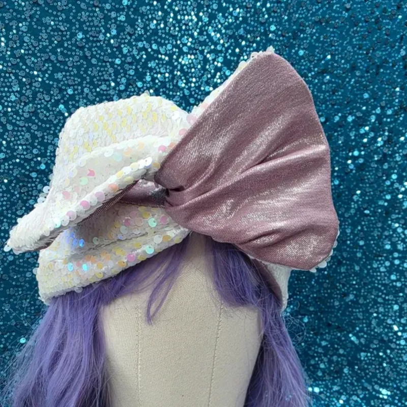 Haaraccessoire met een grote mauve strik en een witte strik met stippen op een blauwe glitterachtergrond.