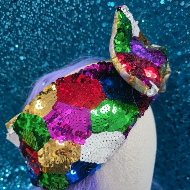 Mannequinhoofd met een kleurrijke paillettenstrik en een zilverkleurige,met goud geborduurde strik op een blauwe achtergrond.
