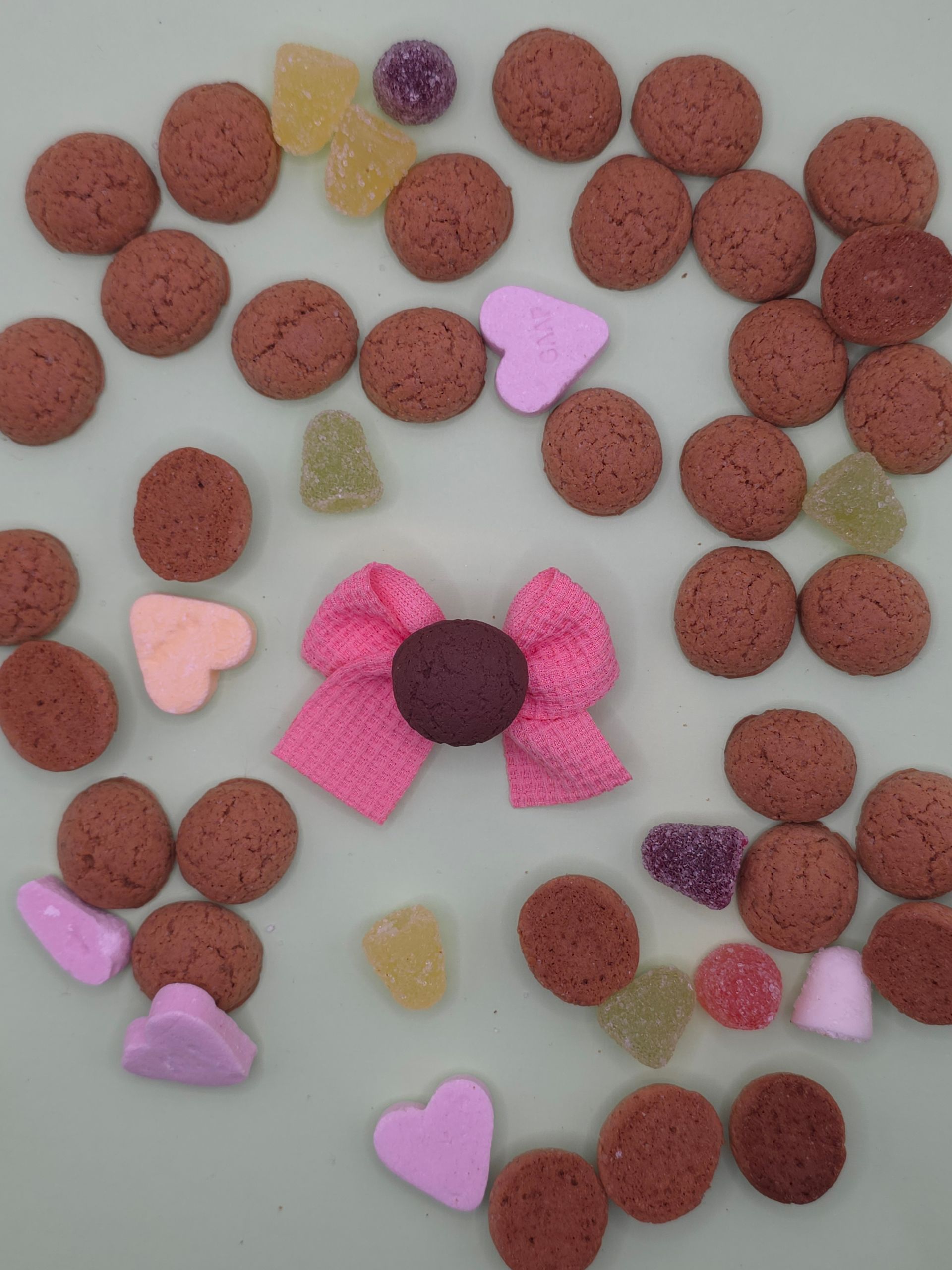 Diverse roze en bruine snoepjes gerangschikt in een hartvormige cirkel op een lichte achtergrond.