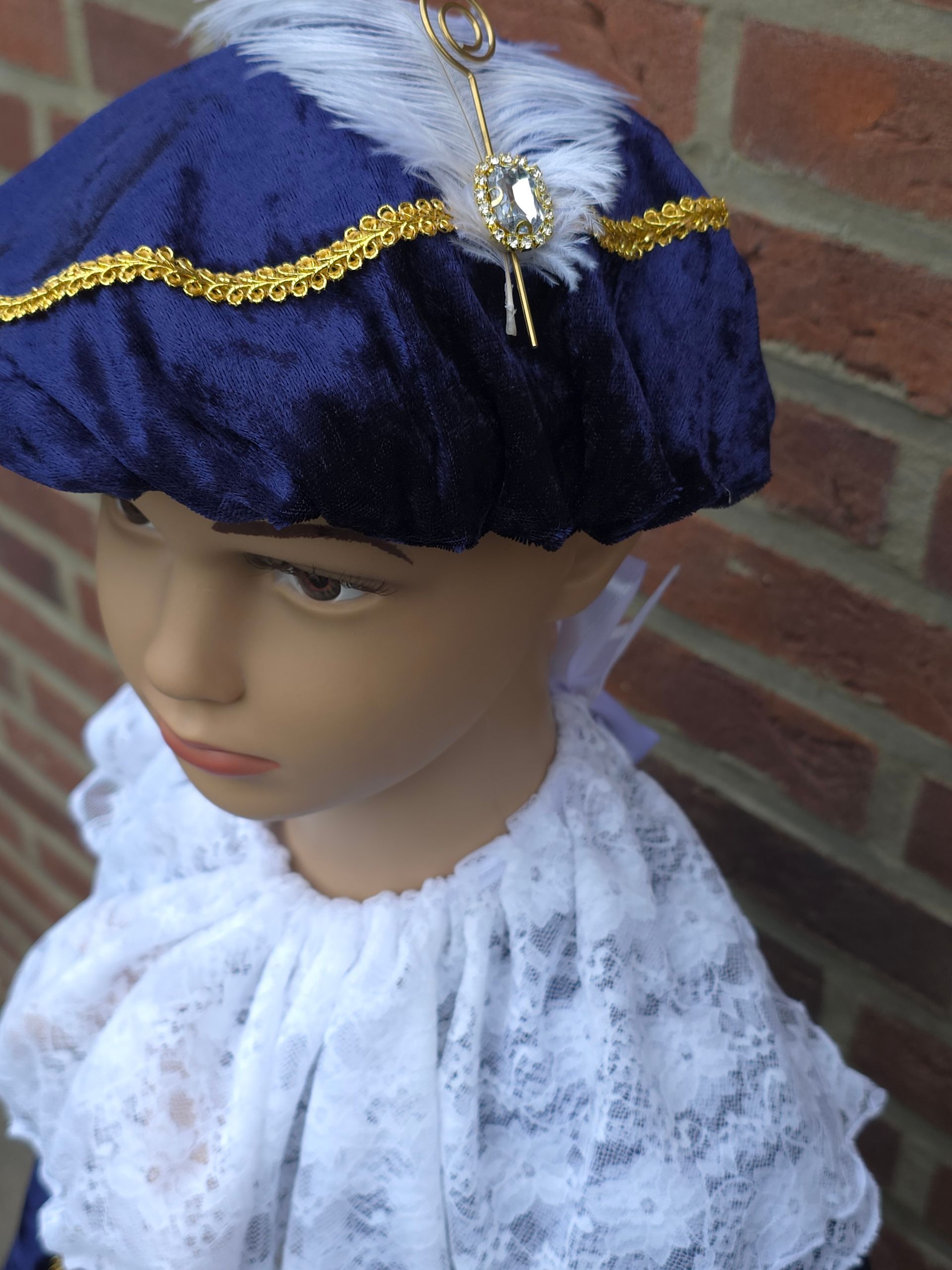 Profiel van een mannequin met een donkerblauwe fluwelen pietenmuts met lavendelkleurig hartornament en een witte kanten top.