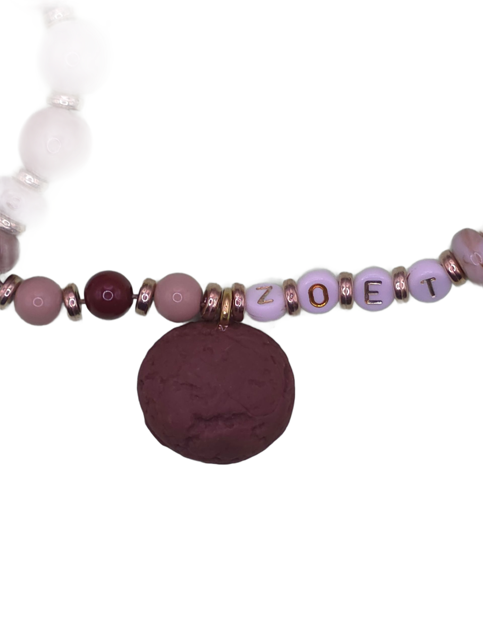 Close-up of a purple beaded necklace with letter beads and a round dark pendant