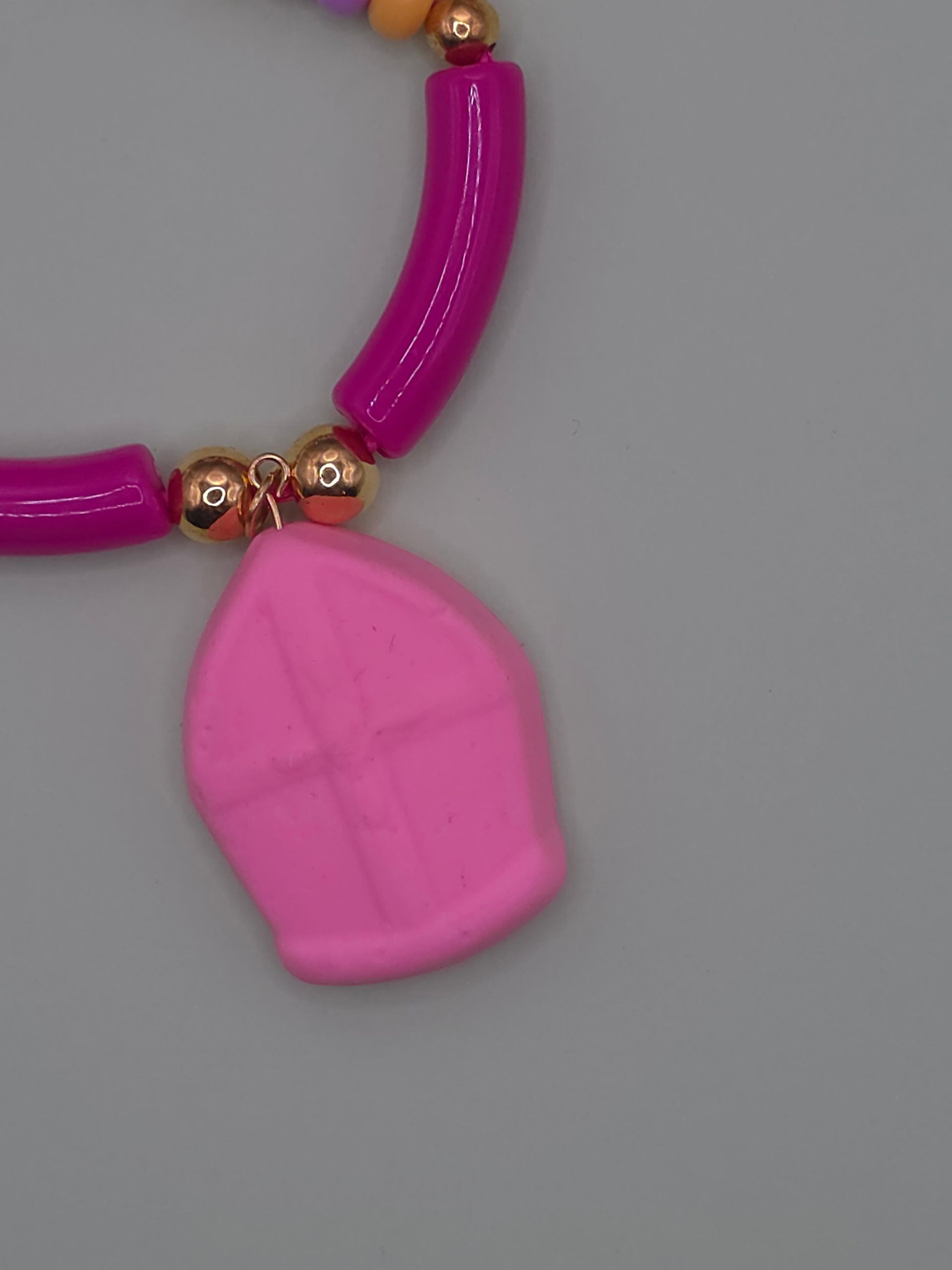Roze kralenketting met een grote roze hanger op een grijze achtergrond.