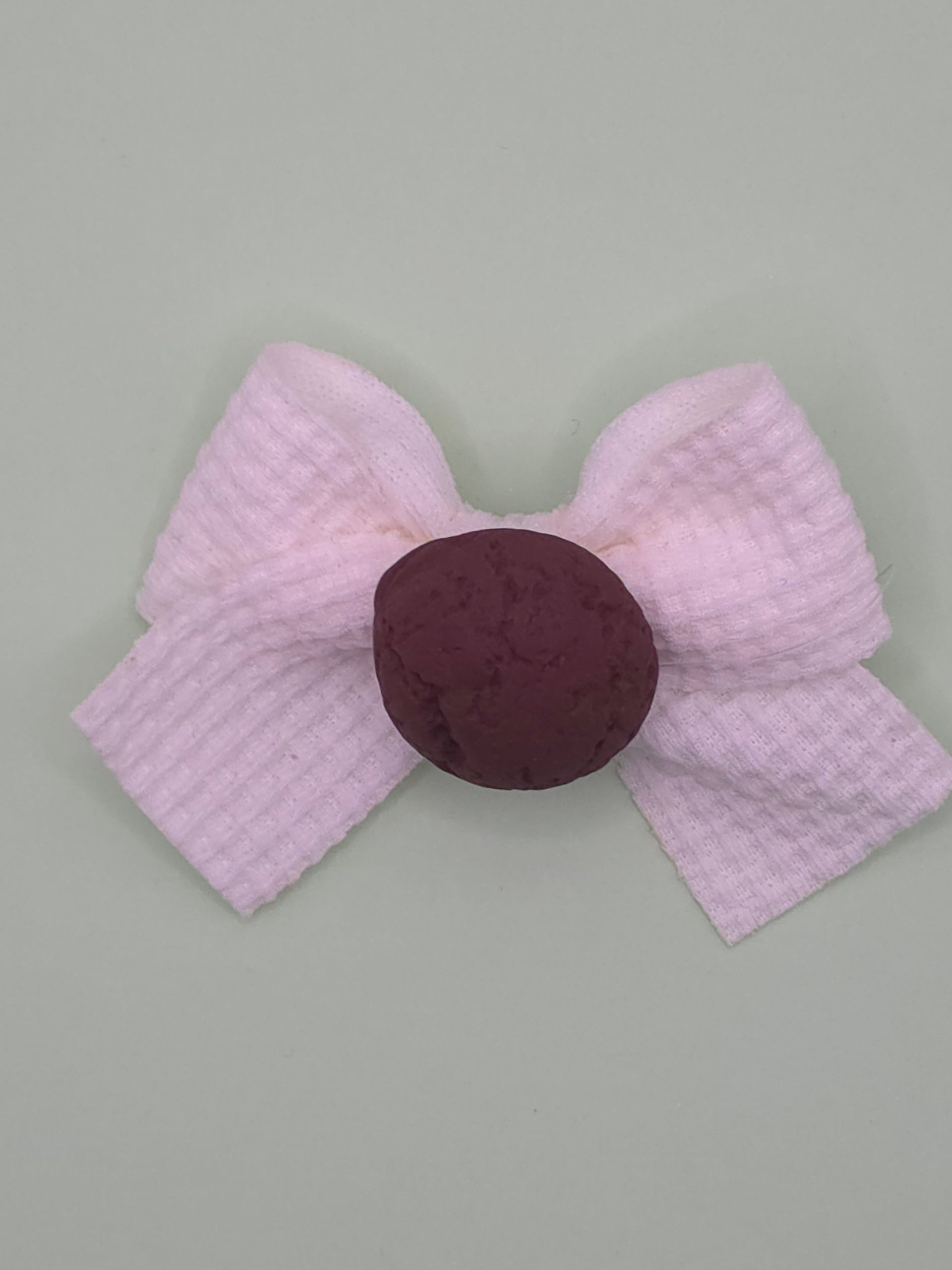 Verspreide rode cornflakesstukjes met pastelkleurige snoephartjes en een roze strikvormig snoepje op een witte ondergrond.