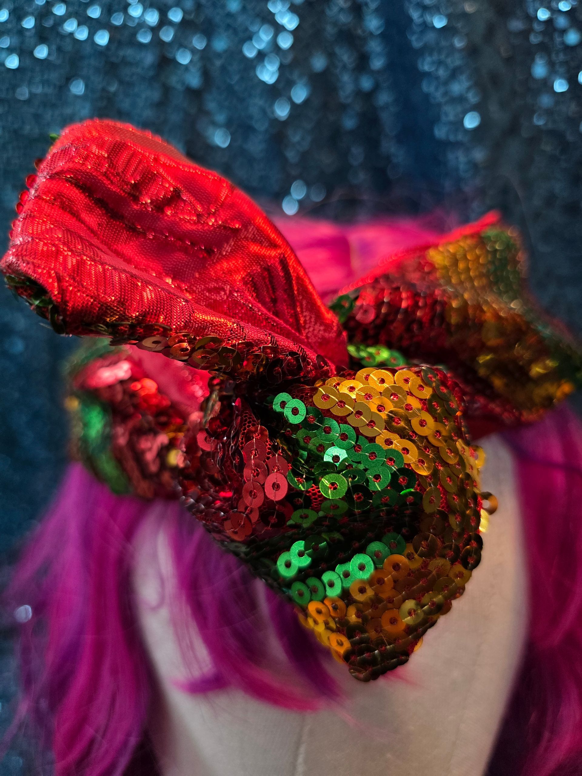 Etalagepoppenhoofd met felroze haar en een veelkleurige strik met pailletten tegen een blauwe glitterachtergrond