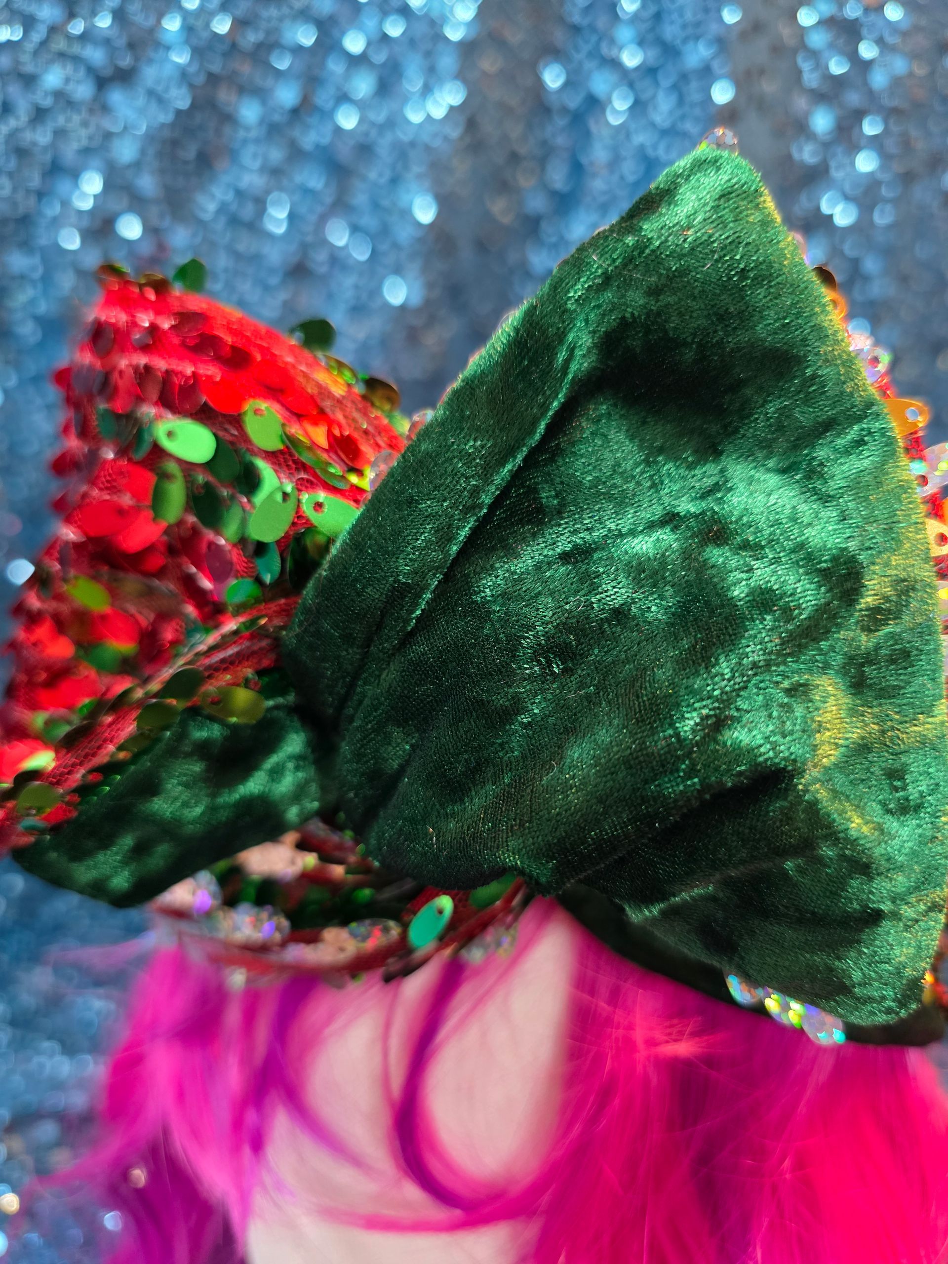Felroze pruik op een paspop met een sprankelend rood, groen en zilver vogelachtig hoofddeksel