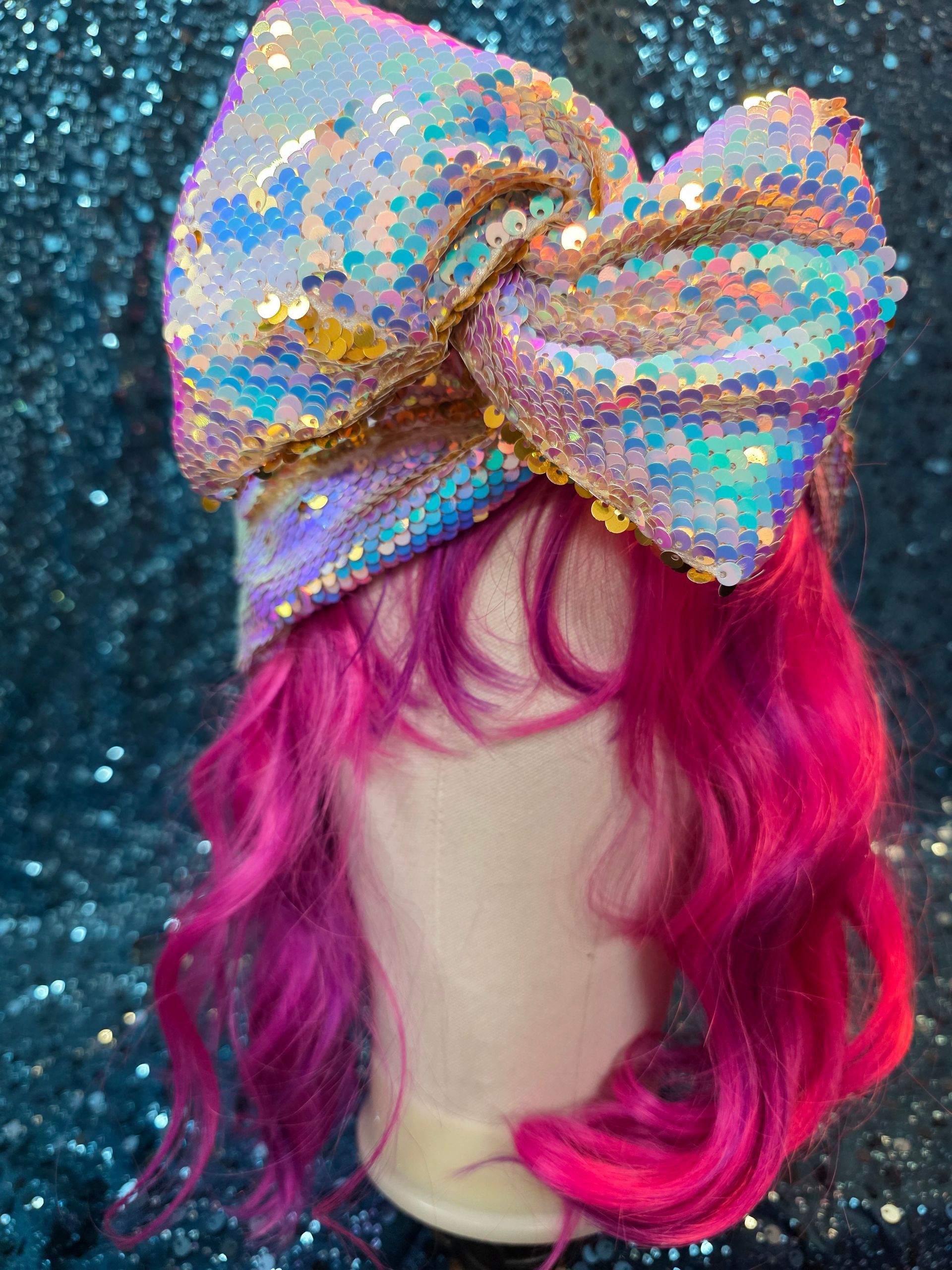 Paspophoofd met felroze haar en een glinsterende regenboogstrik tegen een glitterende turquoise achtergrond