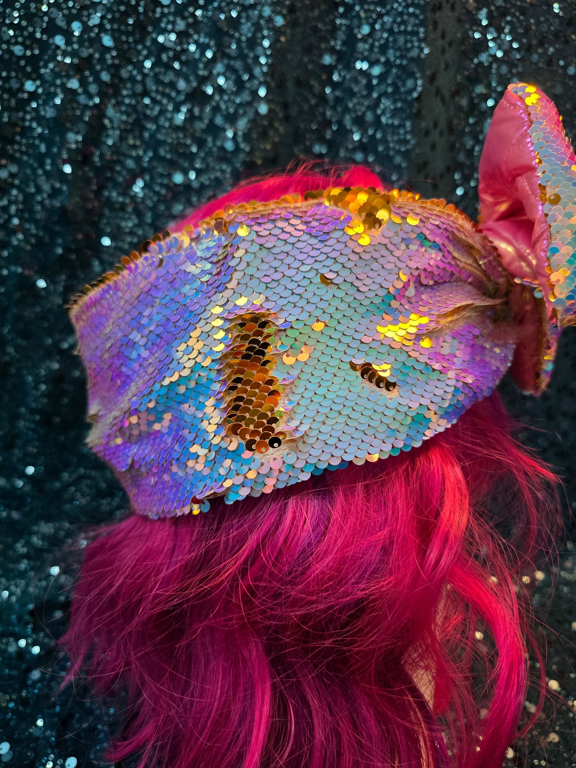 Paspophoofd met felroze haar en een glinsterende regenboogstrik tegen een glitterende turquoise achtergrond