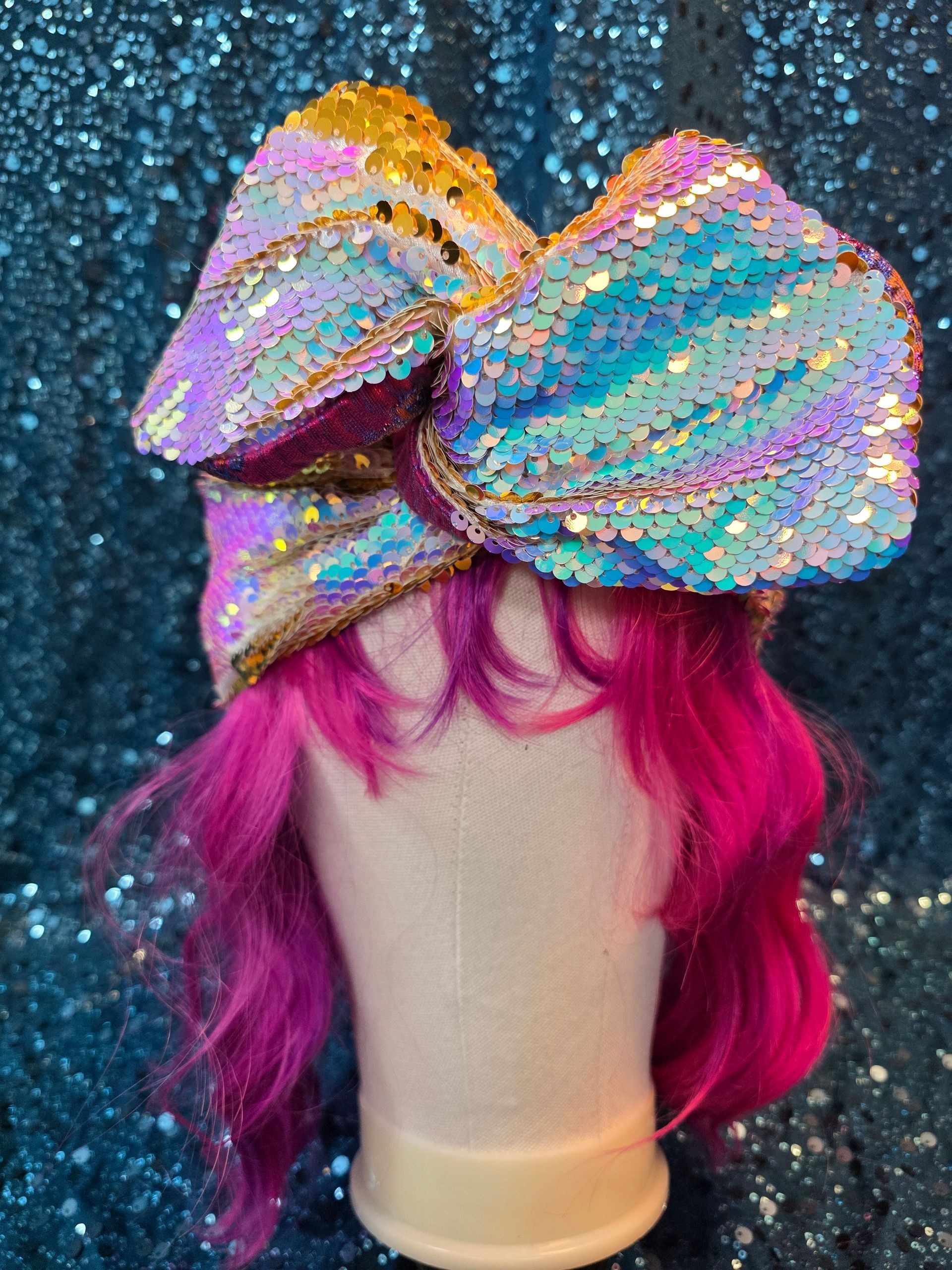 Een glinsterende, veelkleurige strik op een paspophoofd met felroze haar tegen een glitterende donkere achtergrond