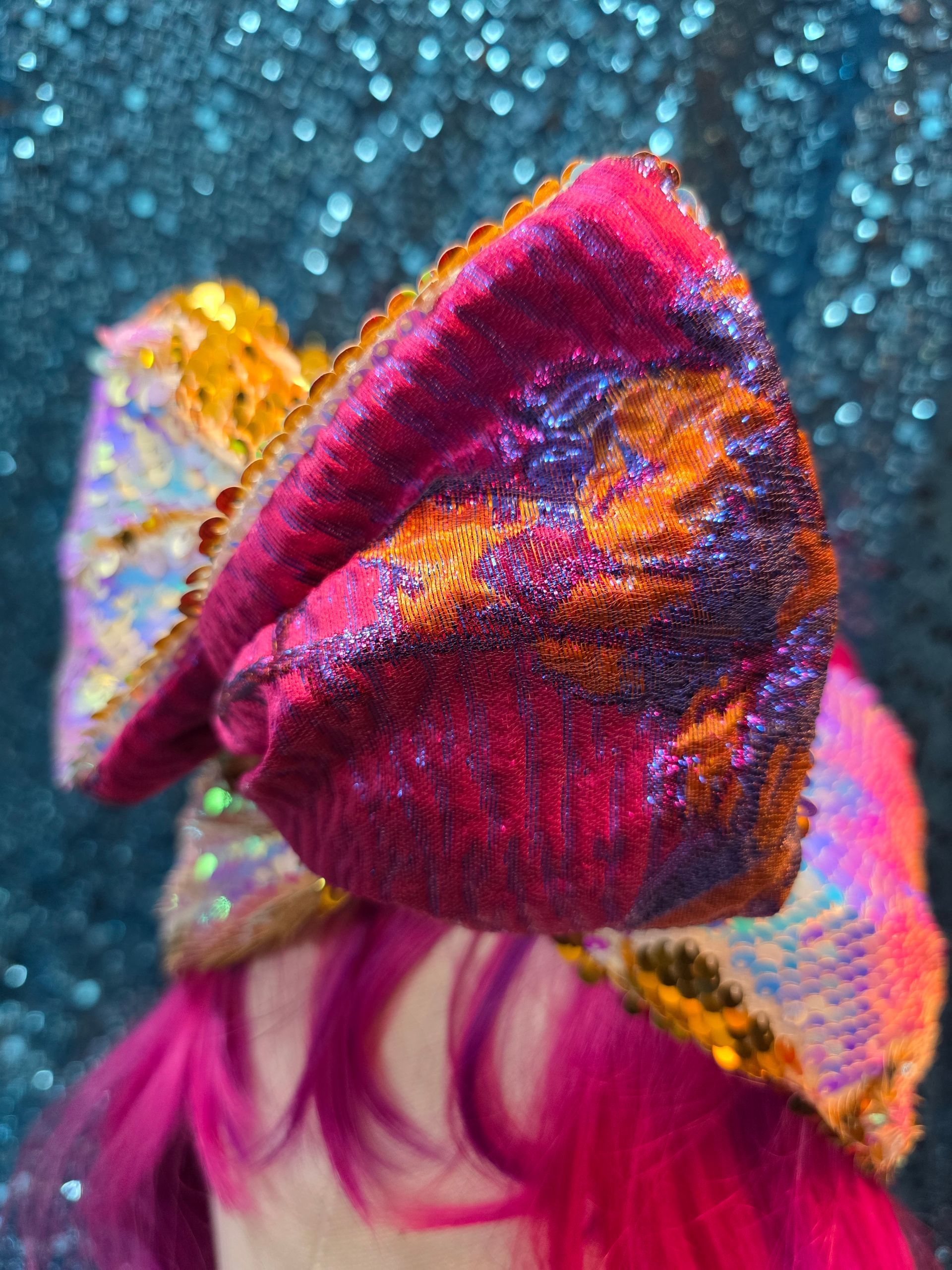 Een glinsterende, veelkleurige strik op een paspophoofd met felroze haar tegen een glitterende donkere achtergrond