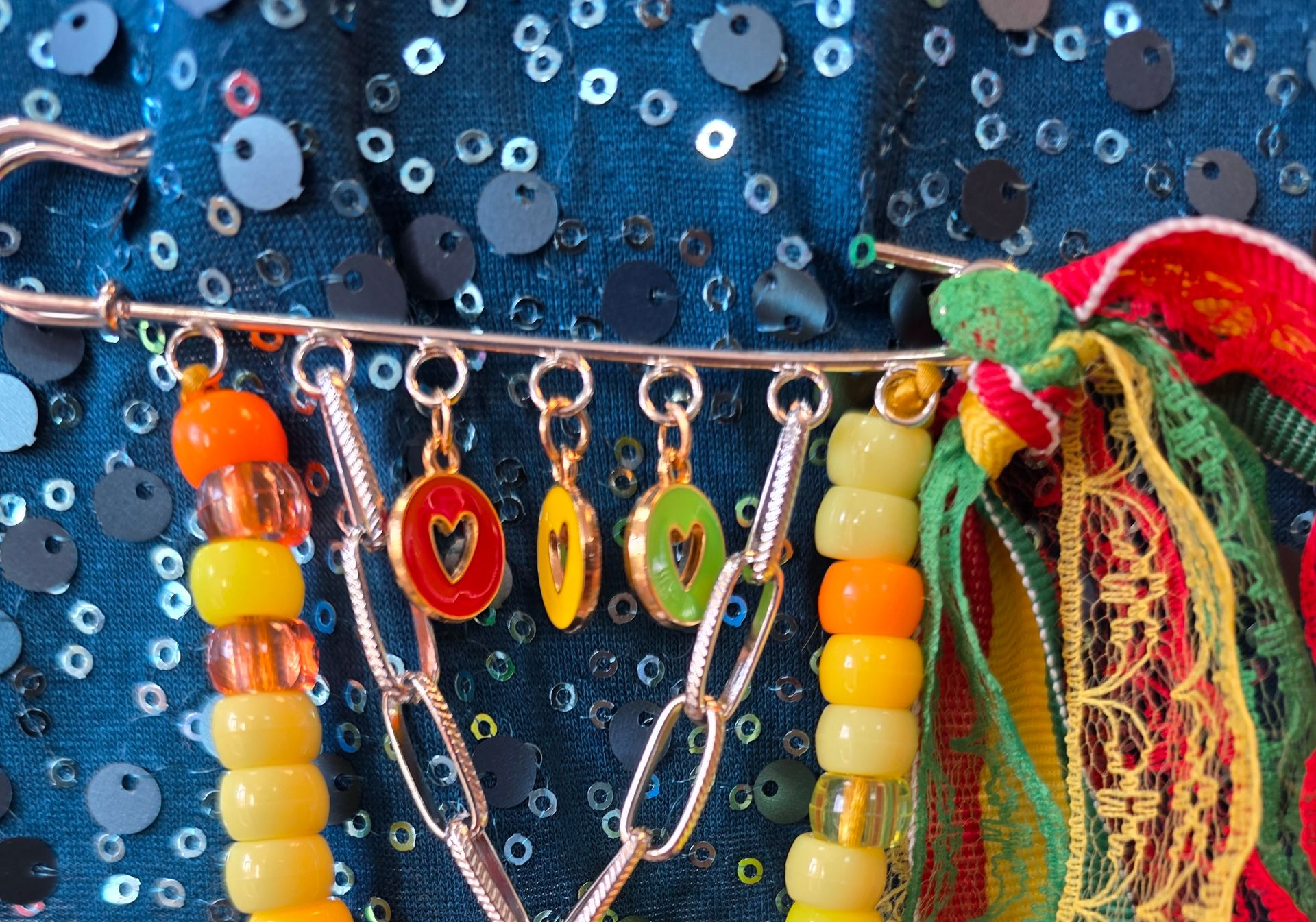 Kleurrijke sieraden met kralen en kwastjes tegen een achtergrond van blauwe paillettenstof