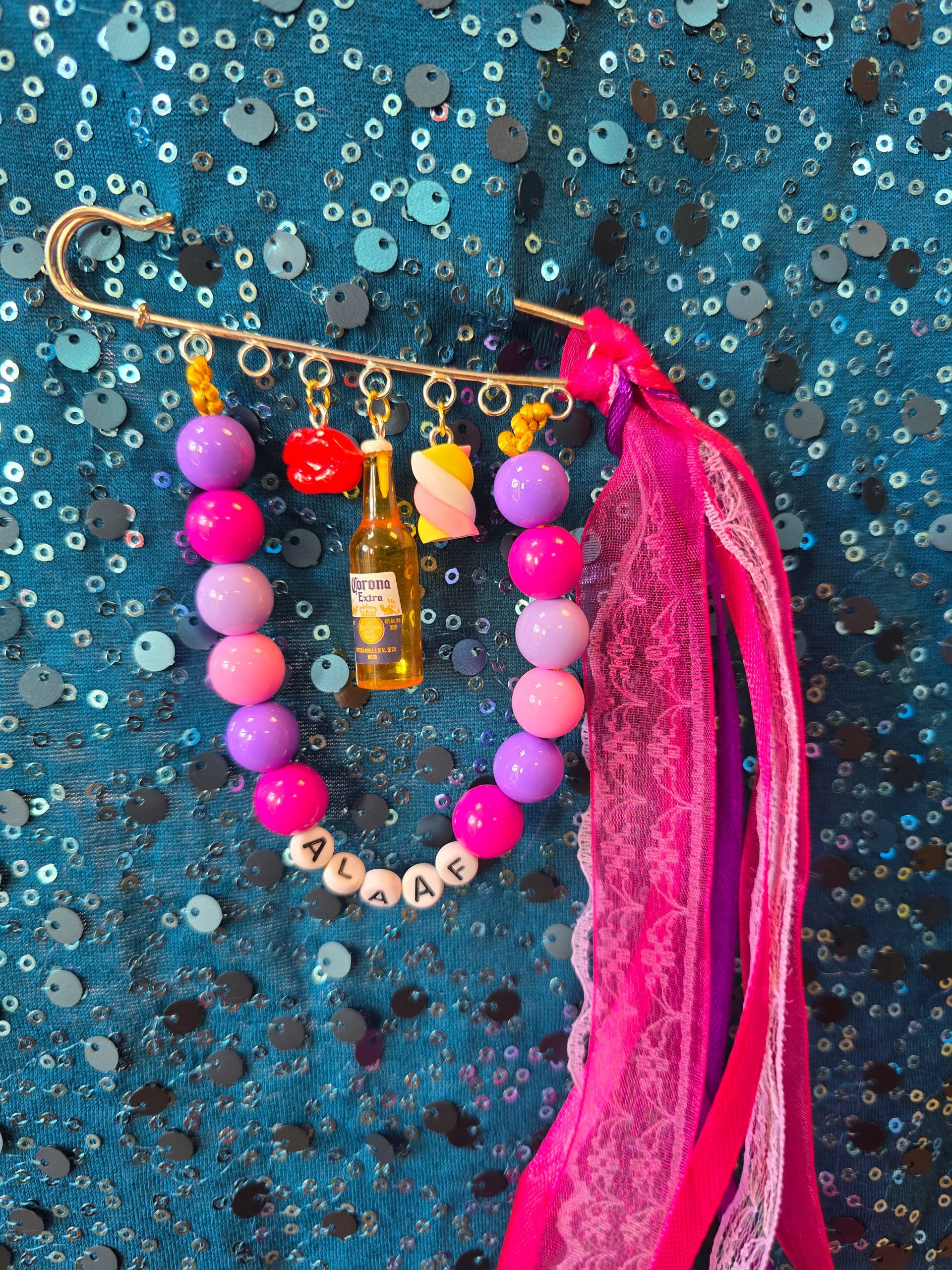 Roze kralenketting met een gouden hanger en kwastje op een blauwe achtergrond met textuur