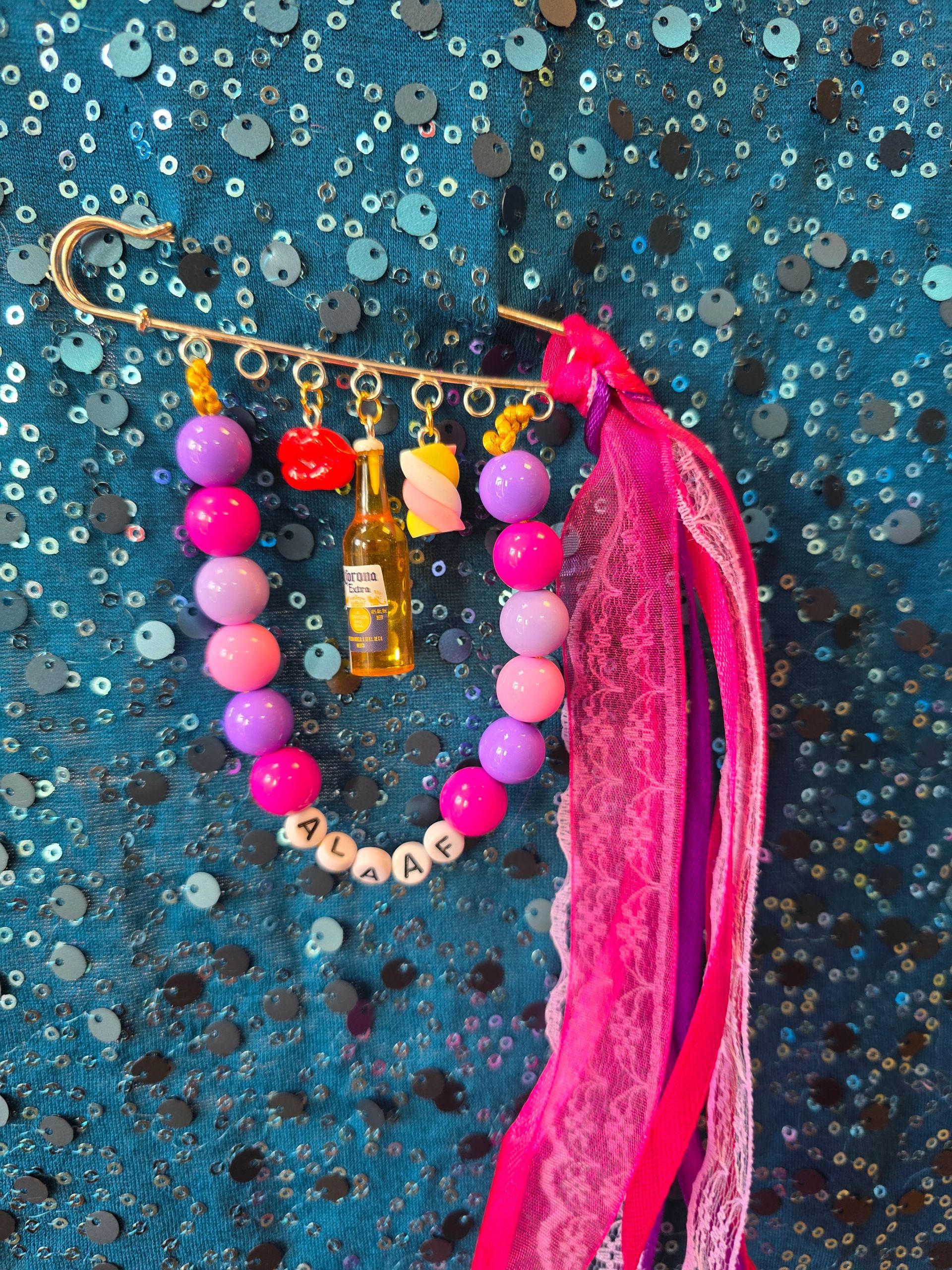 Roze kralenketting met een gouden hanger en kwastje op een blauwe achtergrond met textuur