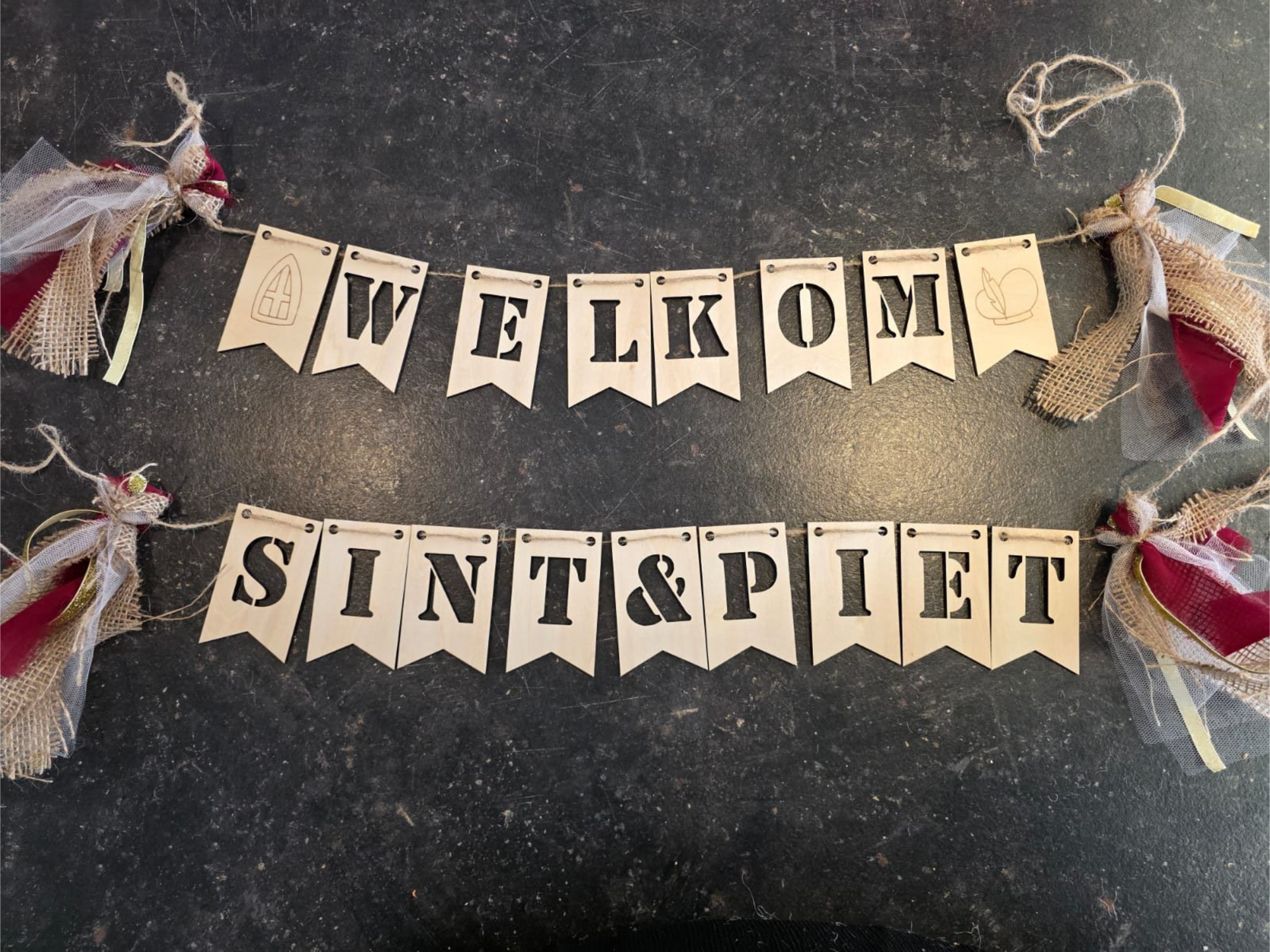 Welkomstbanner met vlaggetjes die in zwart en goud de tekst 