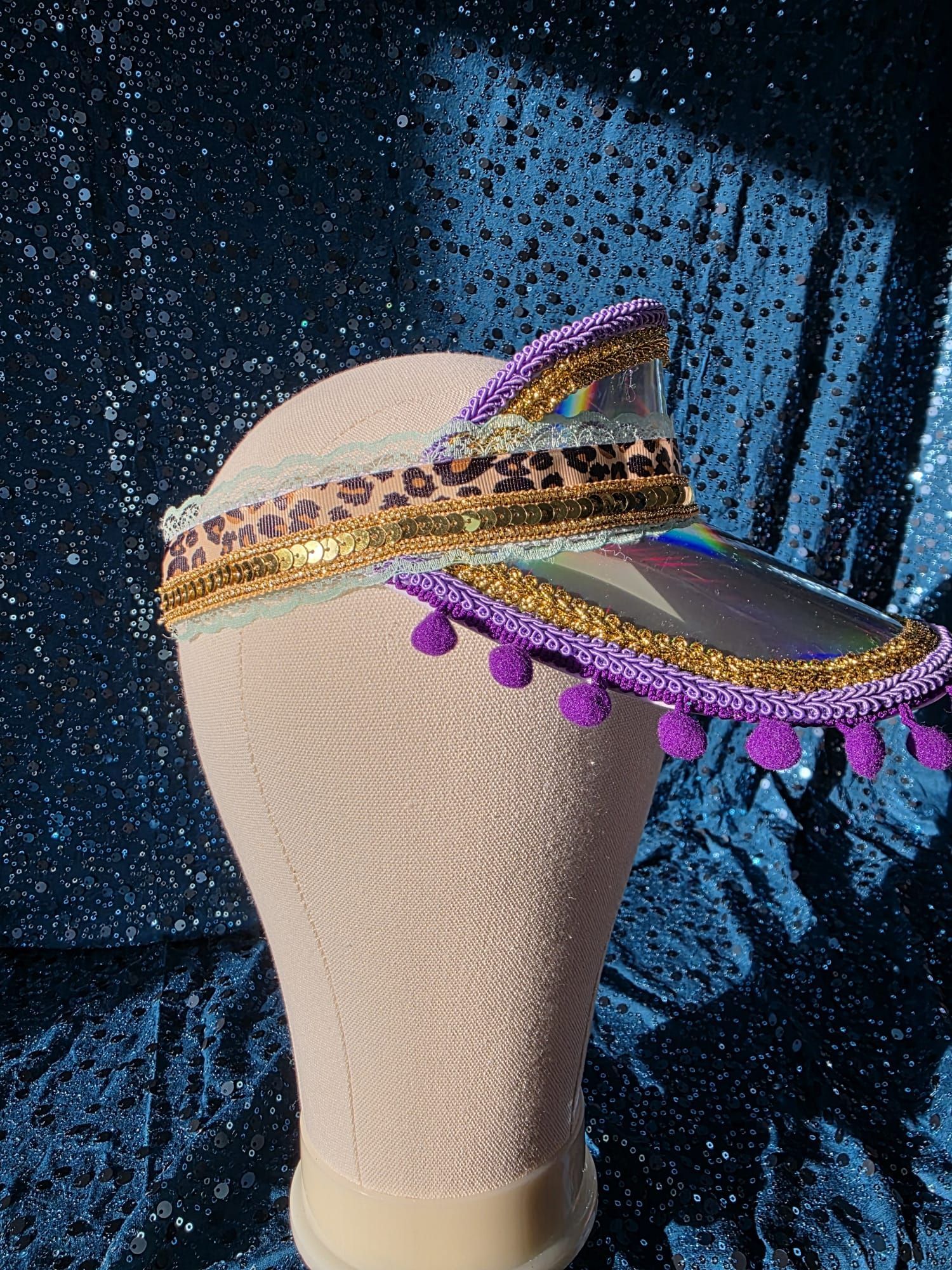 Crèmekleurige, gestructureerde lamp met regenboogkleurige pomponversiering tegen een donkerblauwe, glinsterende achtergrond.