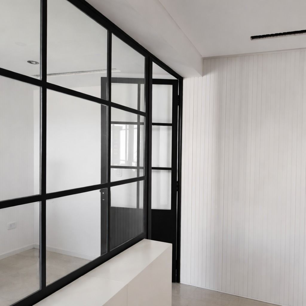 Interior moderno con mampara de cristal con marco negro y paredes revestidas de paneles blancos.
