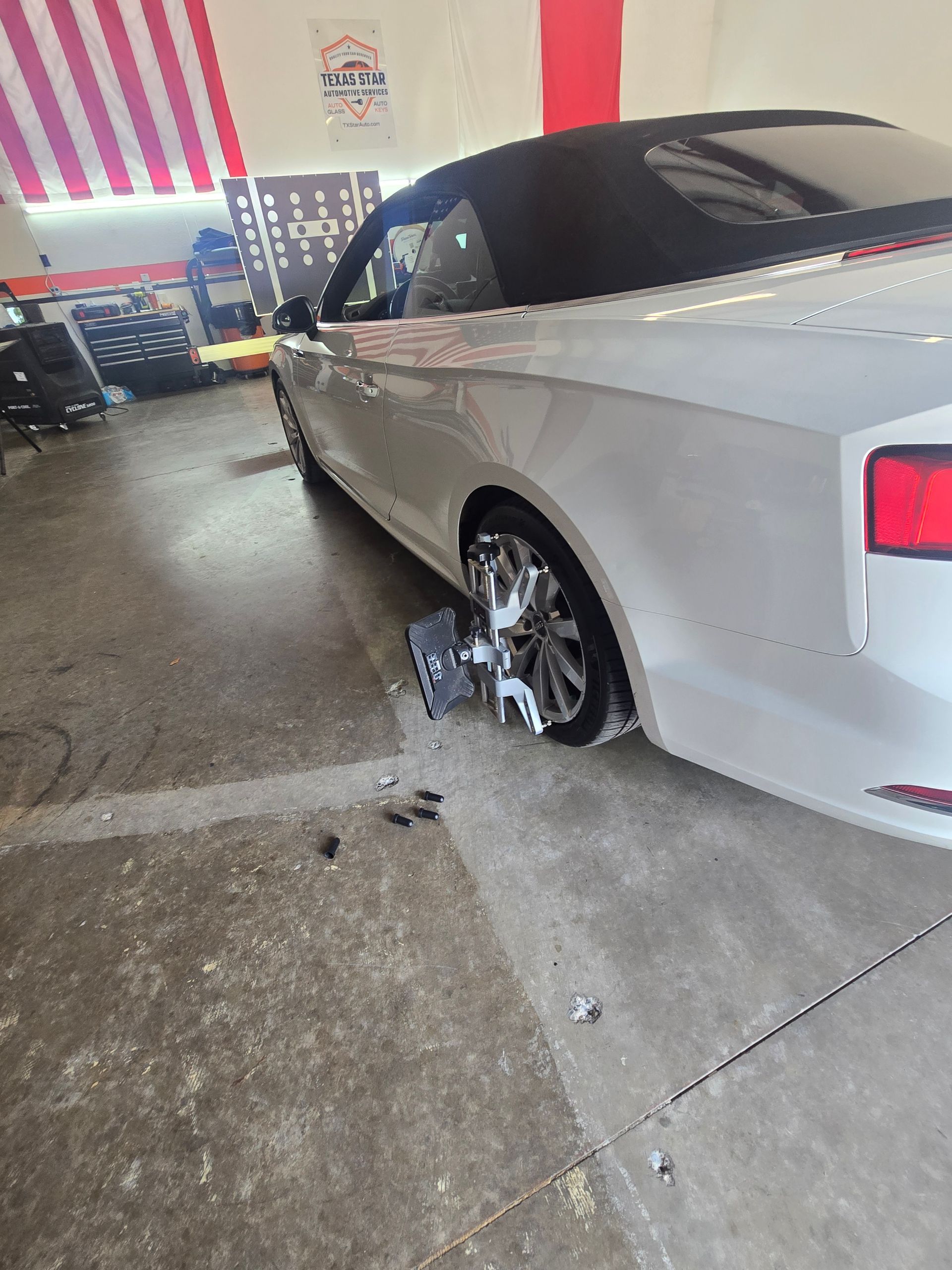 A white car is parked in a garage with a flat tire.