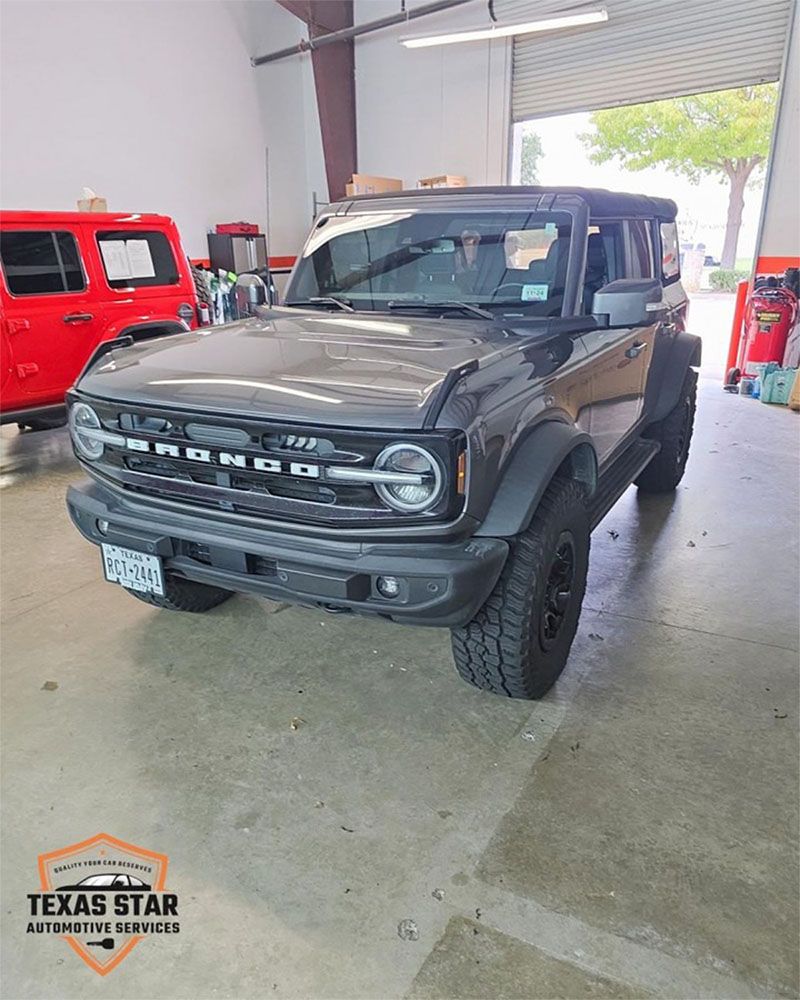 A black ford bronco is parked in a garage.