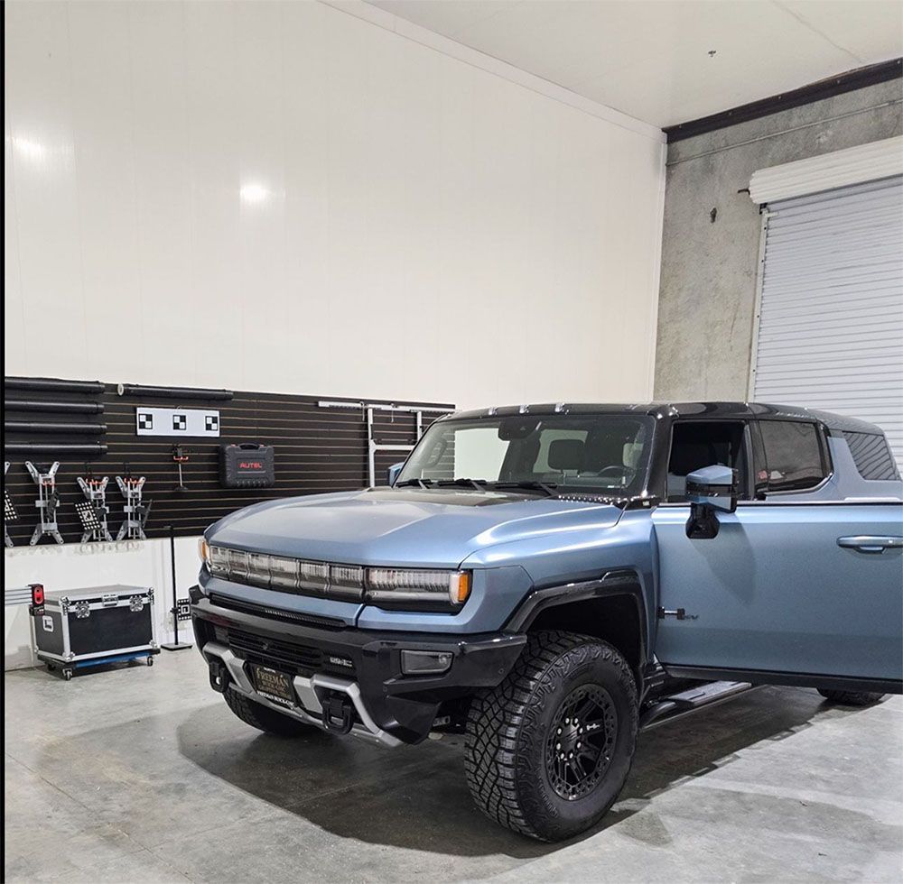 A blue truck is parked in a garage with its doors open
