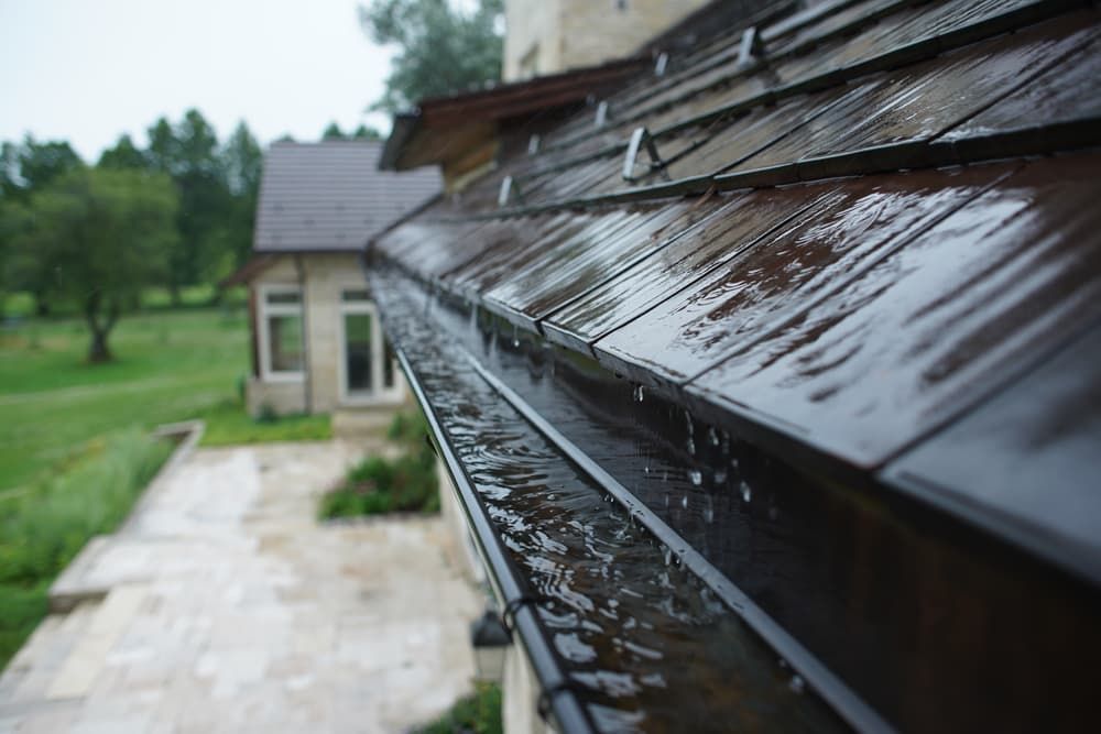 Rain is Falling on a Gutter on the Roof of a House — TK Guttercleaning in Woy Woy, NSW