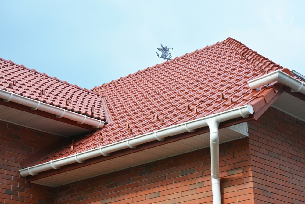 A brick house with a red tiled roof and white gutters — TK Guttercleaning in Wyong, NSW