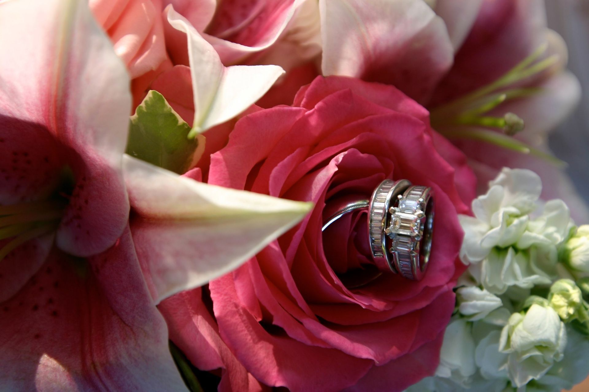Wedding rings on a pink rose bouquet with white flowers