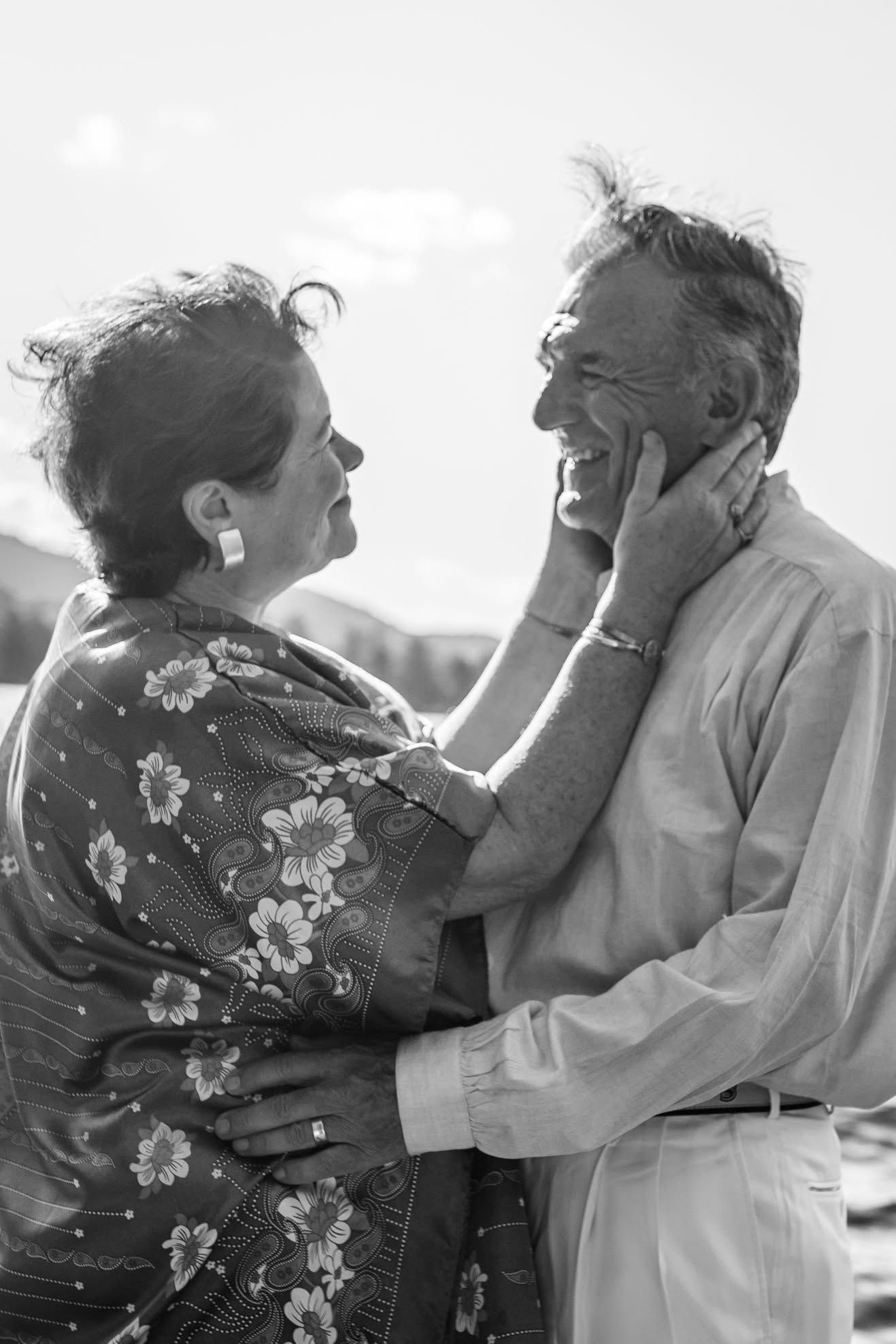 Two people embracing outdoors, smiling and touching faces in black-and-white.