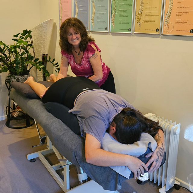 Tina, Spinal Flow practitioner at Akiki Spinal Flow, Sunshine Coast QLD. Massage therapist working on a client on a table in a treatment room