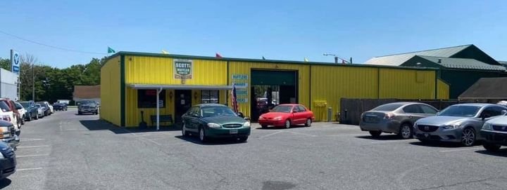 Yellow auto repair shop with parked cars outside on a sunny day