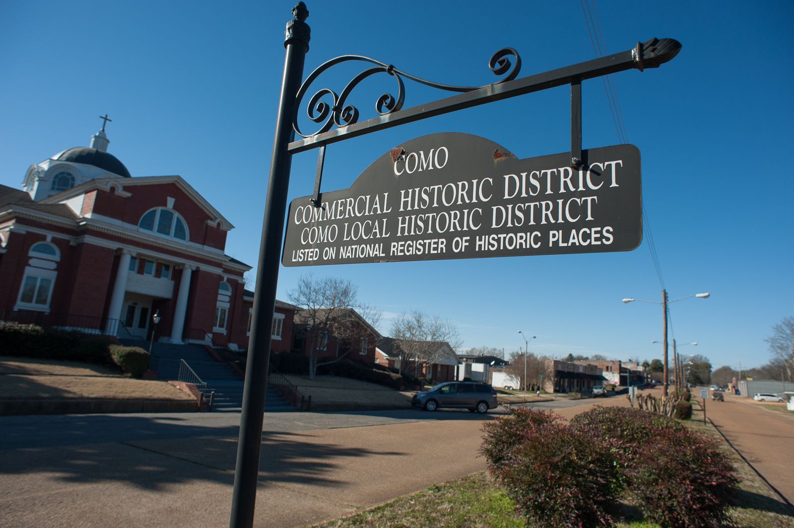 Historic district sign on a street corner beside a brick building under a clear blue sky.