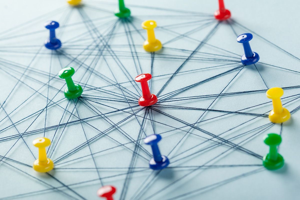 Colorful pushpins connected by threads on a network diagram background
